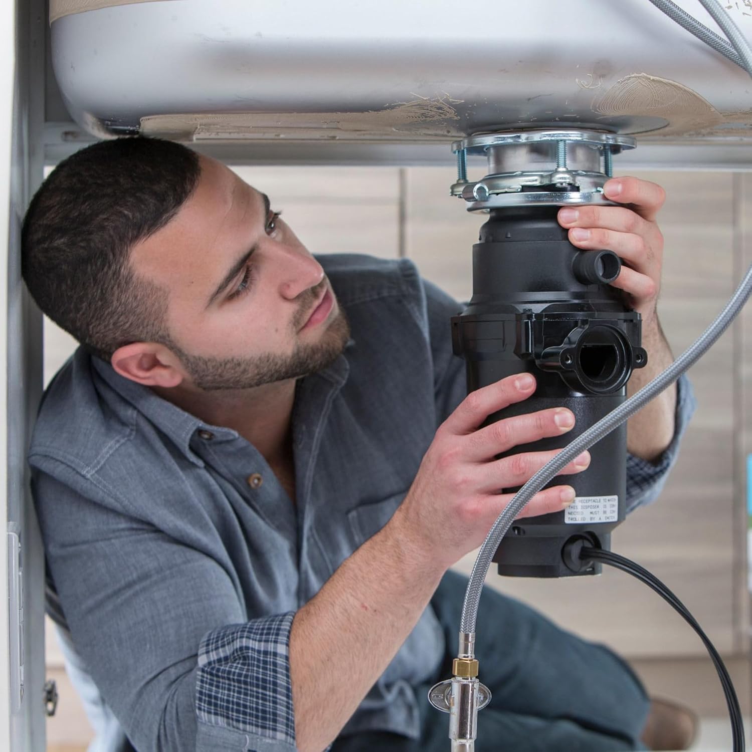 Person installing a Moen continuous feed garbage disposal under a kitchen sink
