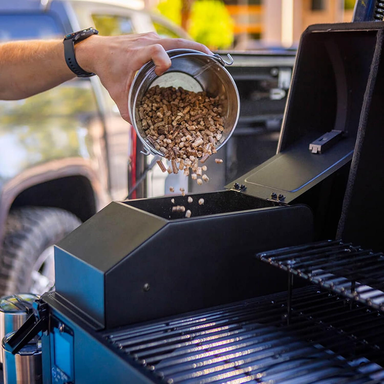 A person pouring wood pellets into the hopper of a Pit Boss pellet grill