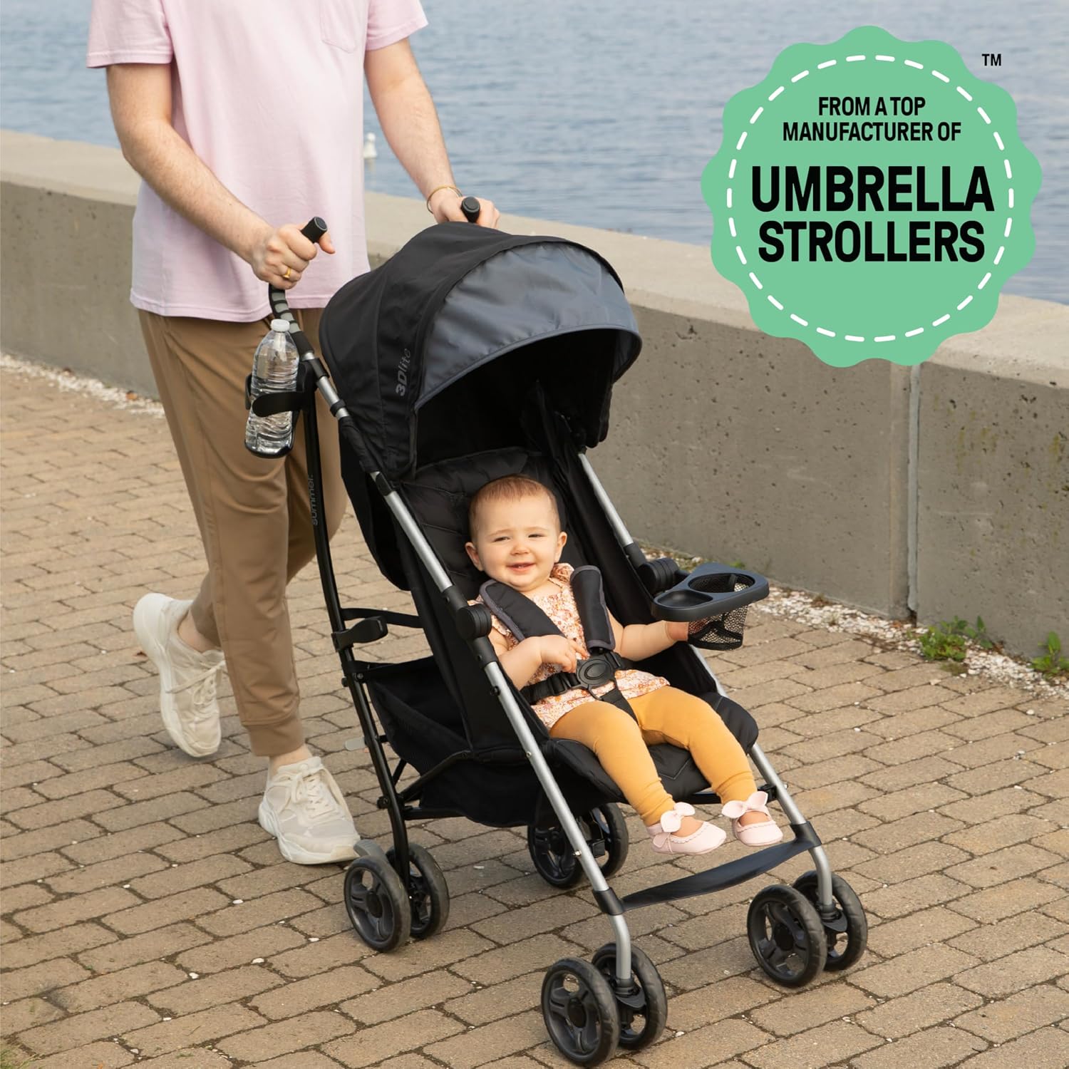 Parent pushing a Summer Infant 3Dlite stroller with a smiling toddler seated inside on a brick path